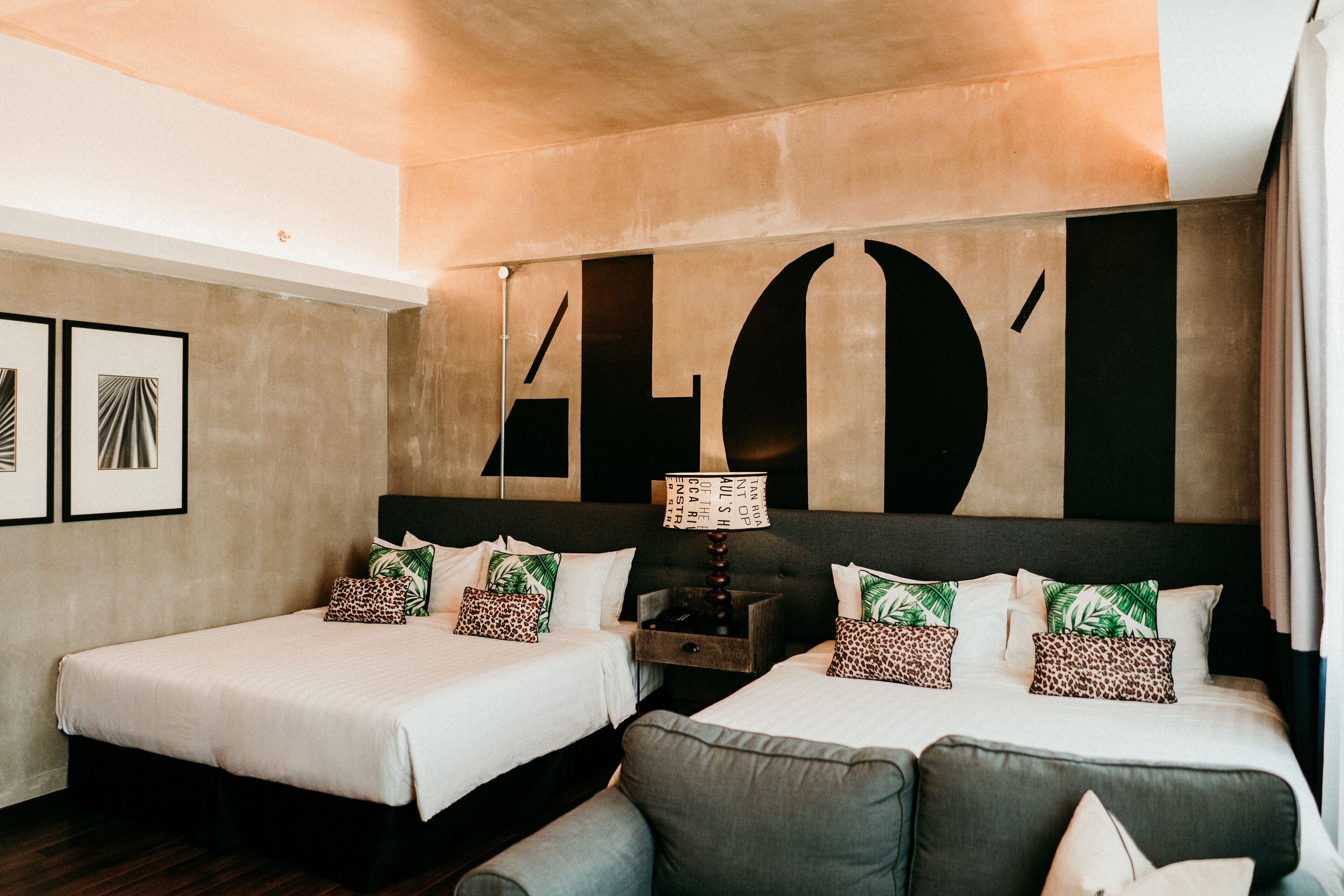 A hotel room with two beds, a sofa, and a large abstract wall art piece.