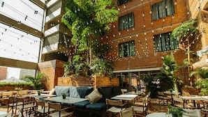 An indoor dining area with brick walls, hanging lights, and green plants. - Rosa Malacca (Malacca City)