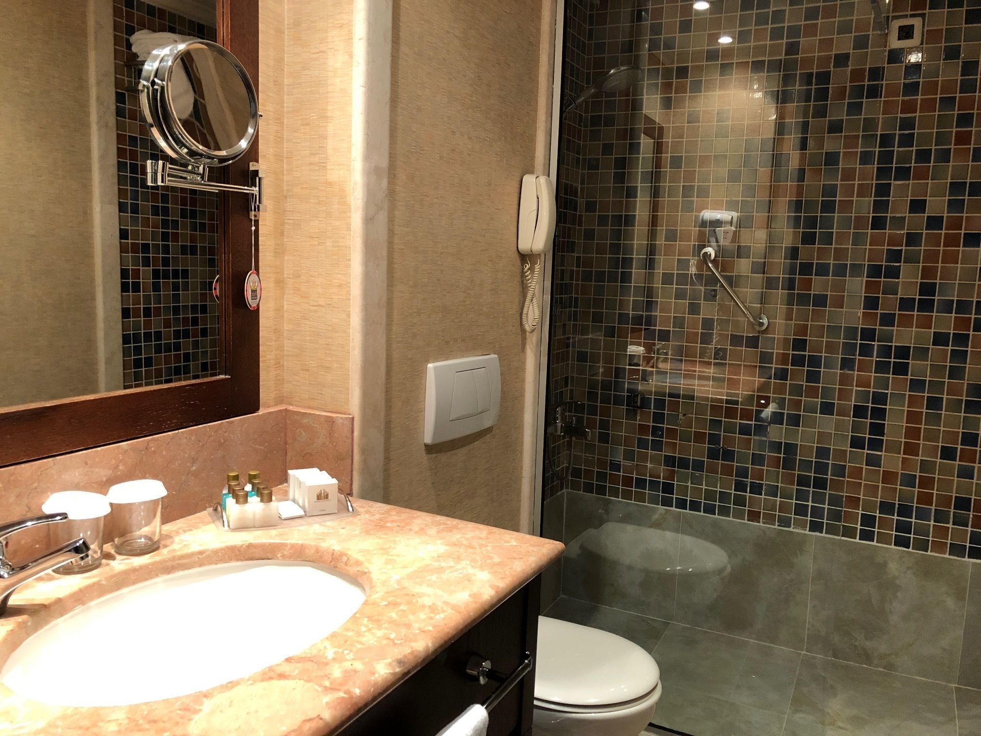 Un baño con lavamanos, espejo y ducha con mosaicos.