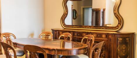Comedor con mesa y sillas de madera, un espejo grande y ornamentado, y un aparador de madera decorativo.
