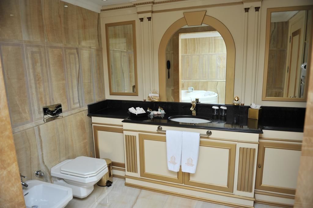 Un baño con tocador de doble lavabo, un espejo grande y un inodoro.