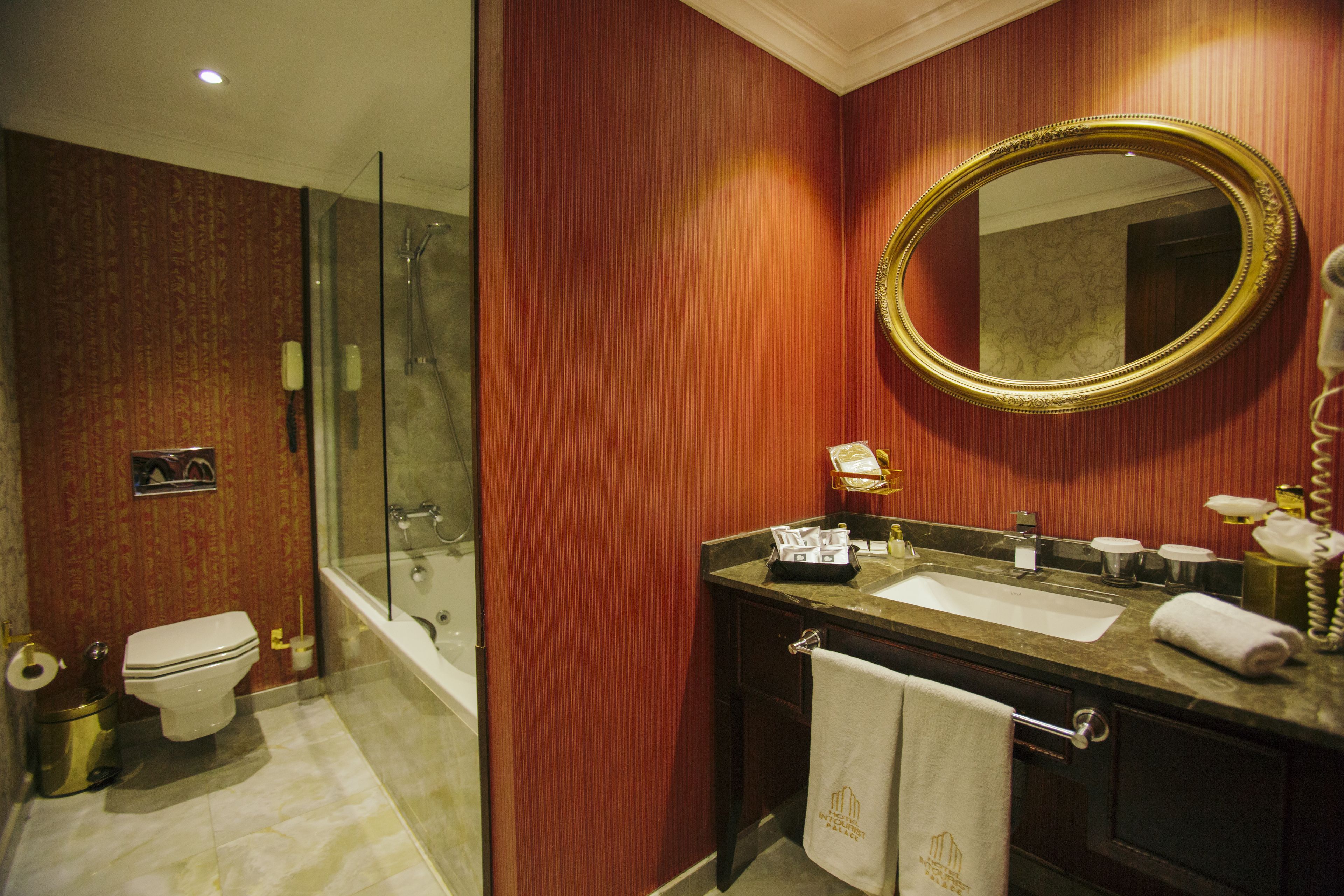 A bathroom with a glass-enclosed shower, a sink with a vanity, and a large mirror.