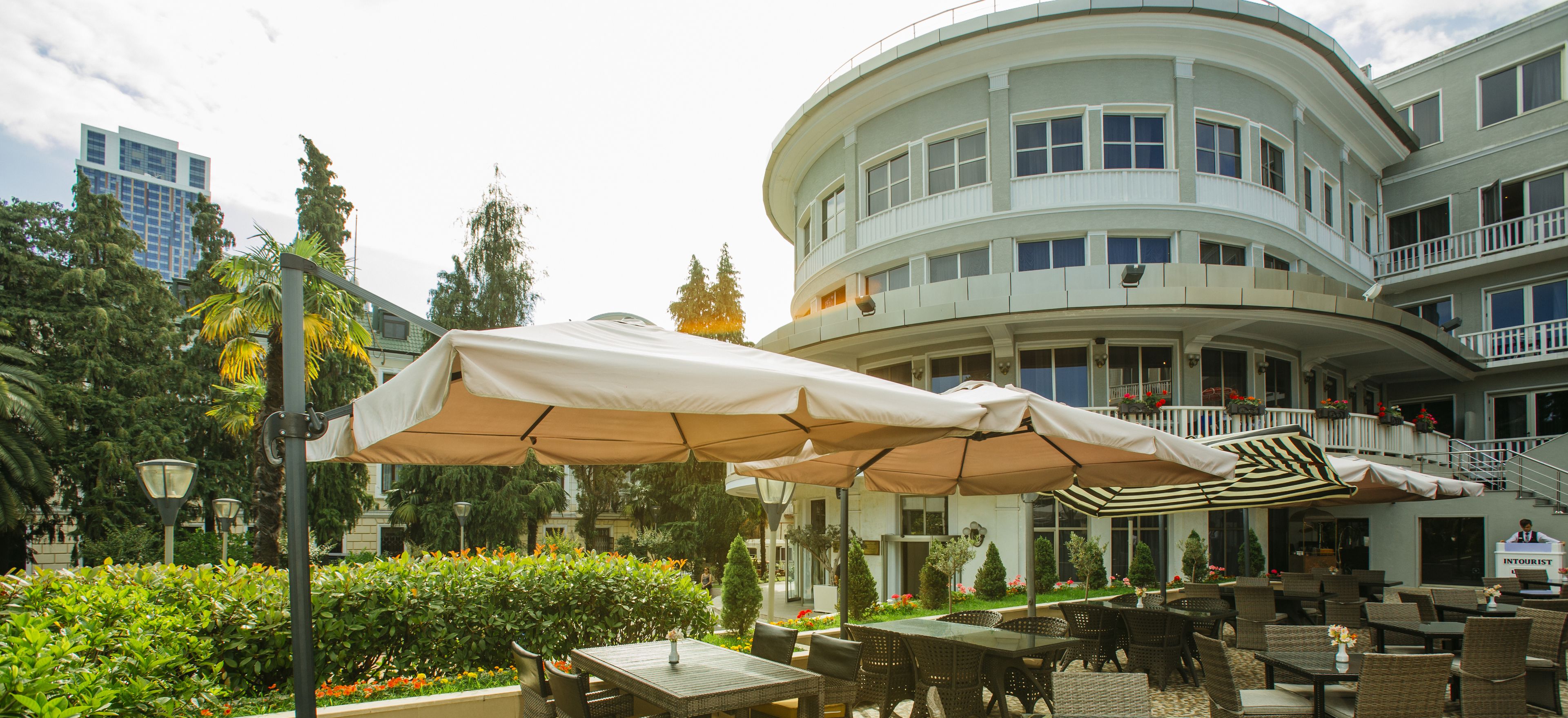 A hotel courtyard with outdoor seating, a curved building, and a sign for the concierge.
