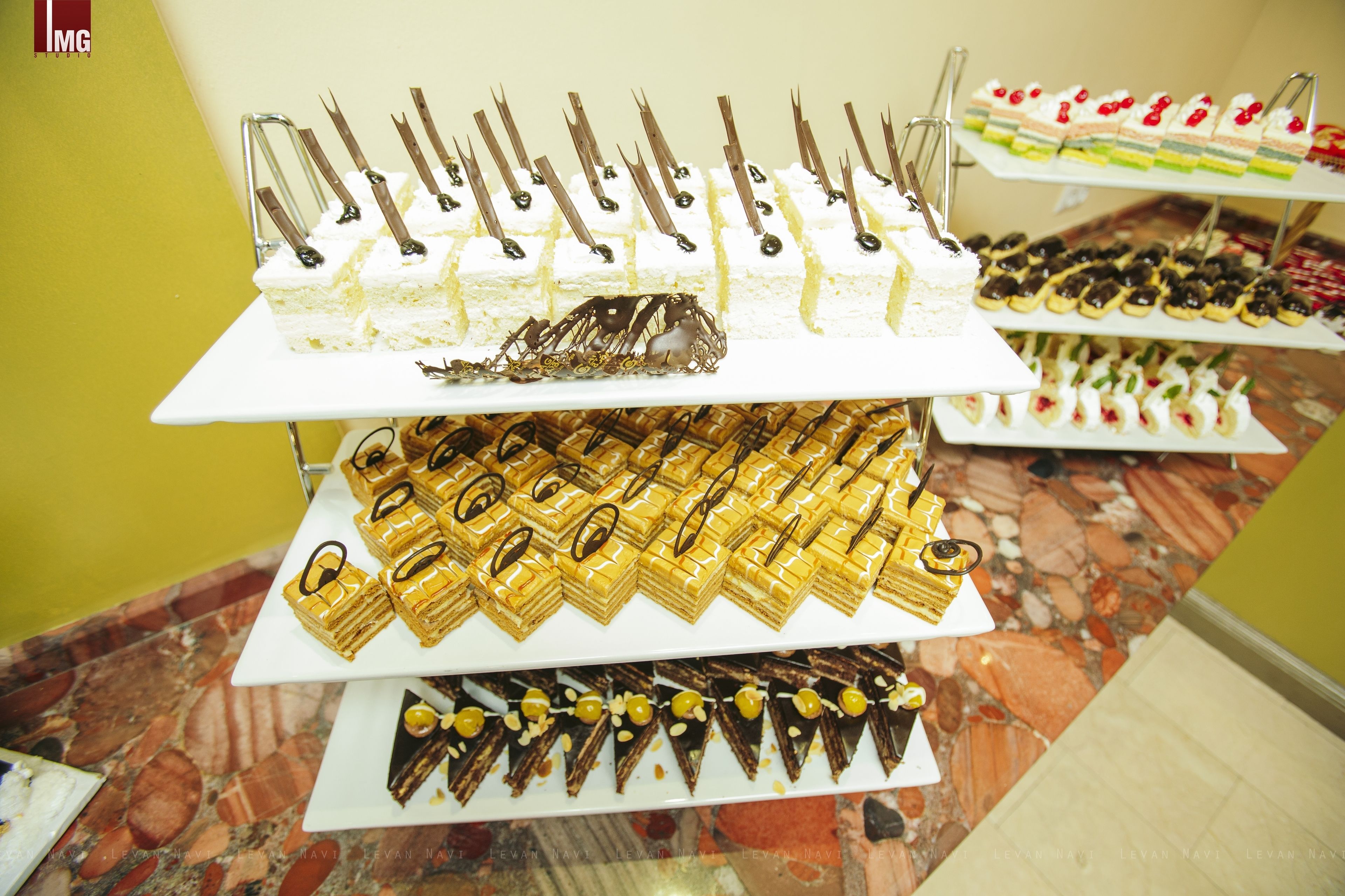 A multi-tiered display of various desserts on a marble-tiled table.