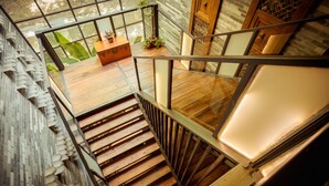 A modern staircase with glass railings, wooden steps, and a view of a wooden deck with plants. - Moonlit Sky Resort (Guilin)