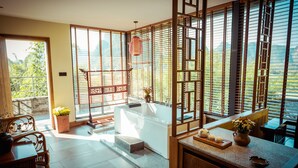 A modern bathroom with a bathtub, a sink, and a window with a view of greenery. - Moonlit Sky Resort (Guilin)