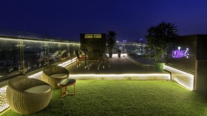 A rooftop terrace with outdoor seating, a small stage, and a neon sign. - The Raintree Dhaka (Dhaka)