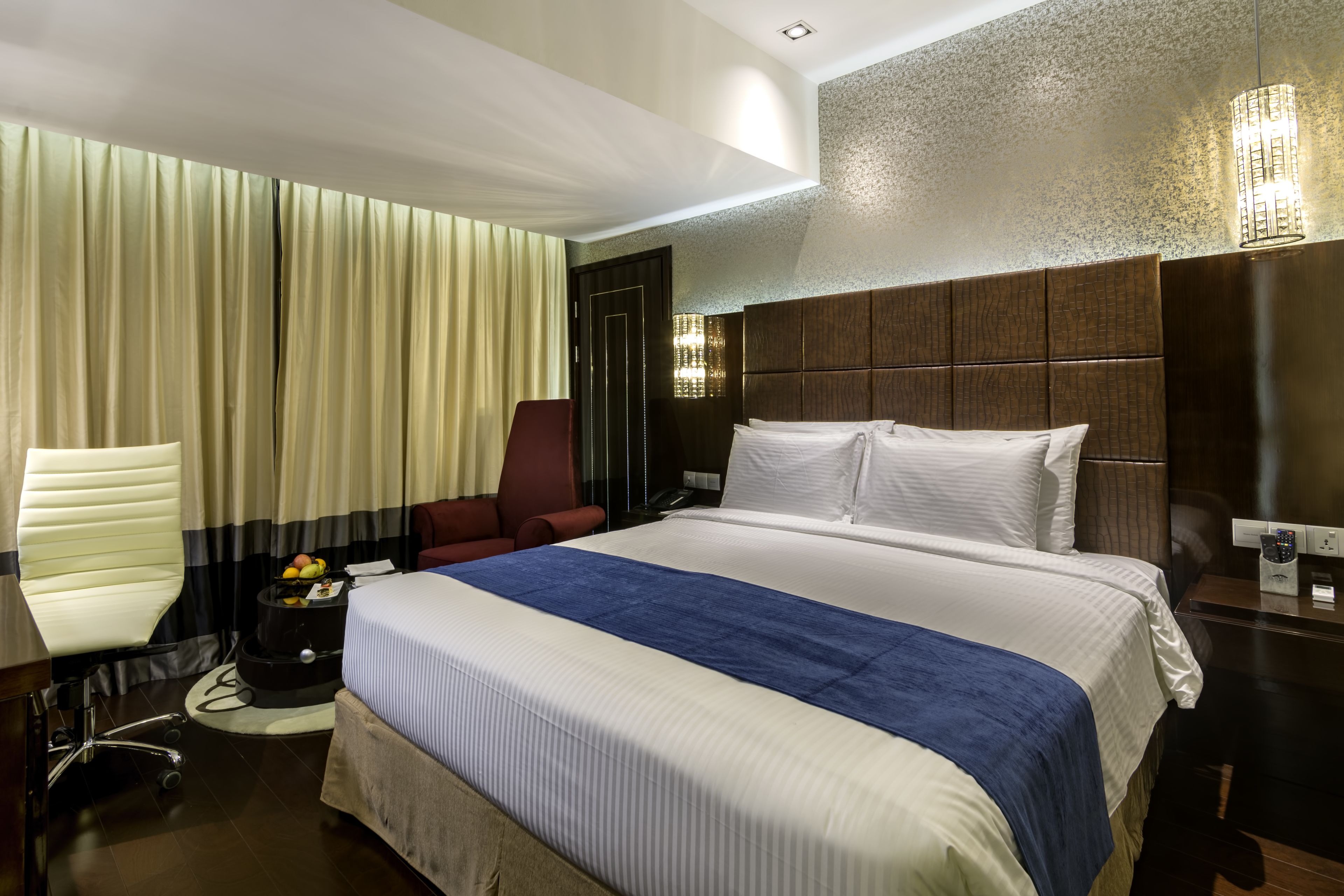 Una habitación de hotel con una cama grande, un escritorio, una silla y una lámpara de escritorio.