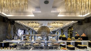 A buffet setup with multiple food stations, a central decorative piece, and a modern chandelier. - The Raintree Dhaka (Dhaka)