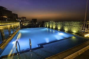 Una piscina infinita en la azotea con vista a la ciudad al atardecer.