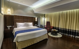Habitación de hotel con una cama grande, un escritorio, una silla y una mesita con frutero.