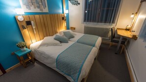 A neatly arranged hotel room with a bed, bedside table, lamp, and a small desk with a chair. - Hôtel Auberge du Morge (Les Echelles)