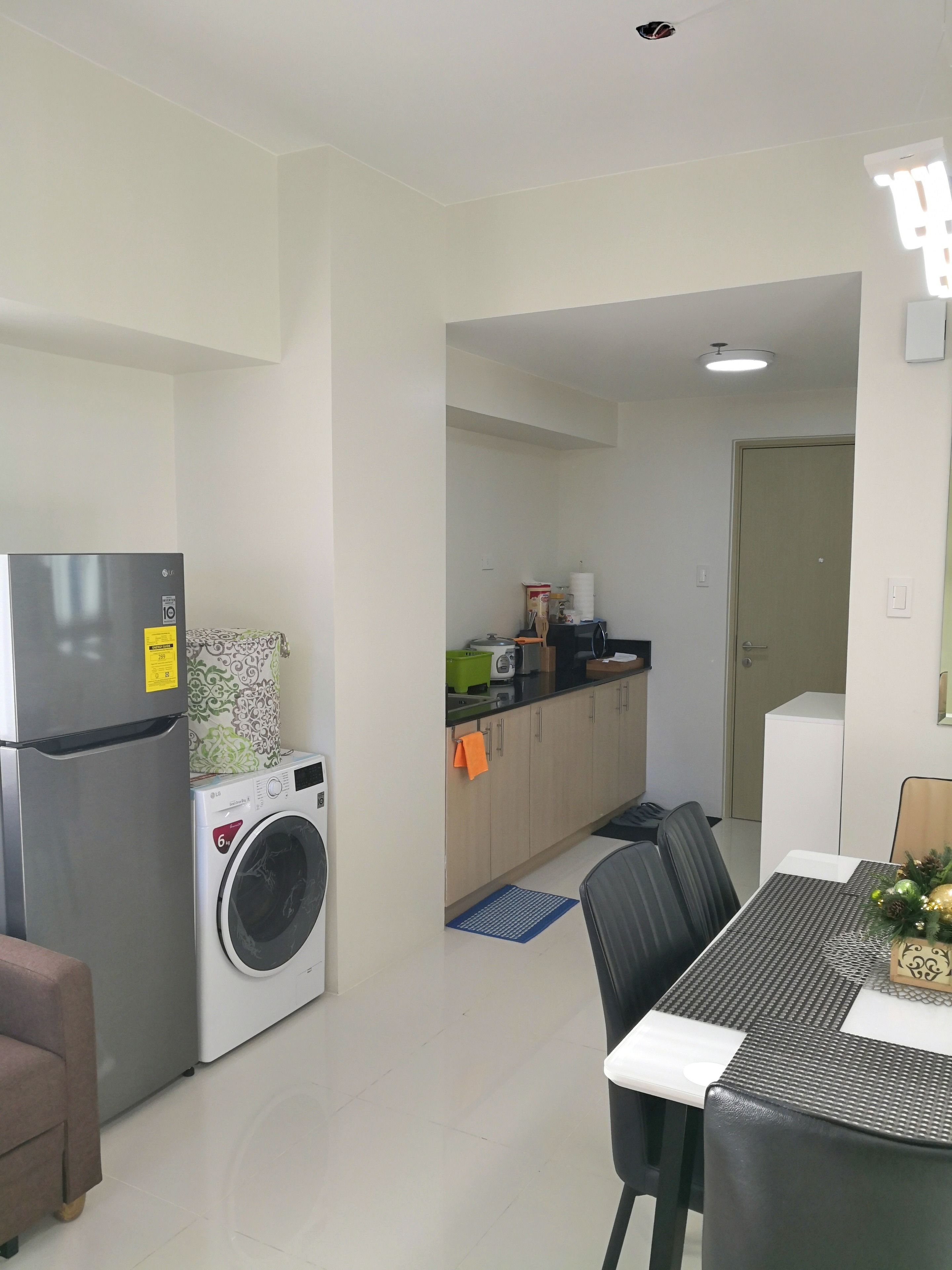 A compact kitchen with a refrigerator, washing machine, and a small countertop with various items.