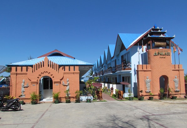 A hotel with a traditional architectural style, featuring a prominent entrance with statues and a blue-roofed building.