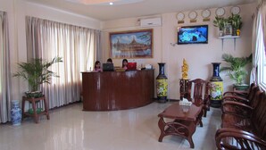 A reception area with a wooden desk, chairs, a television, and decorative vases. - Kyauk Phyu Palace Resort Hotel (Kyaukpyu)