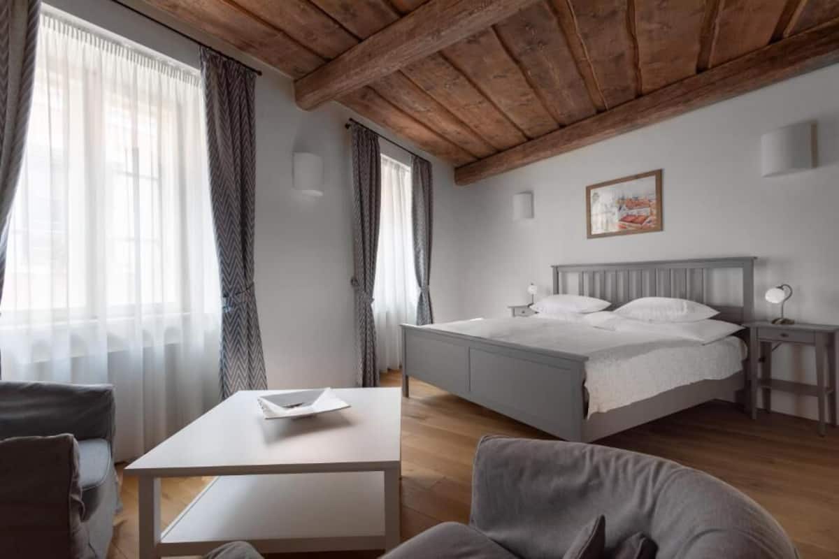 Un dormitorio con cama, mesita de noche y ventana con cortinas.