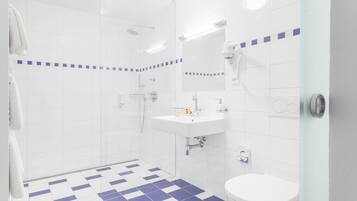 A modern bathroom with a checkered floor, a white sink, a toilet, and a glass shower enclosure.