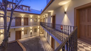 A multi-story building with a checkered floor pattern, a balcony with a wrought iron railing, and a wooden door. - Hotel At the White Lily (Prague)