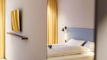 Ein modernes Hotelzimmer mit einem Bett, einem Nachttisch, einer Lampe und einem Spiegel an der Wand.