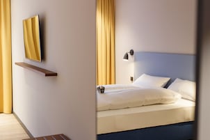 Una habitación de hotel con una cama, una mesita de noche, una lámpara y un espejo en la pared.
