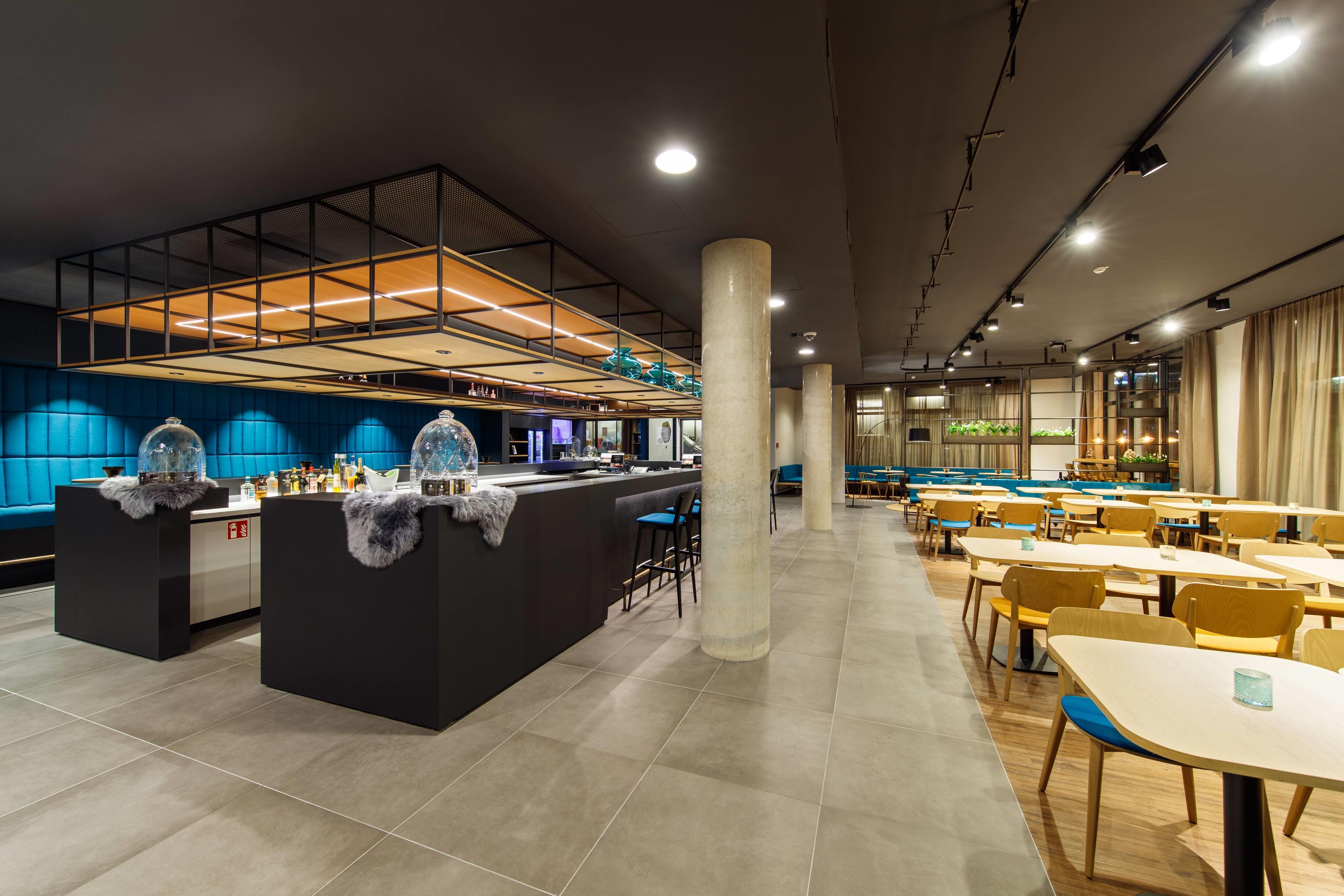 Un restaurante moderno con barra central, disposición de mesas y un techo alto con luminarias.