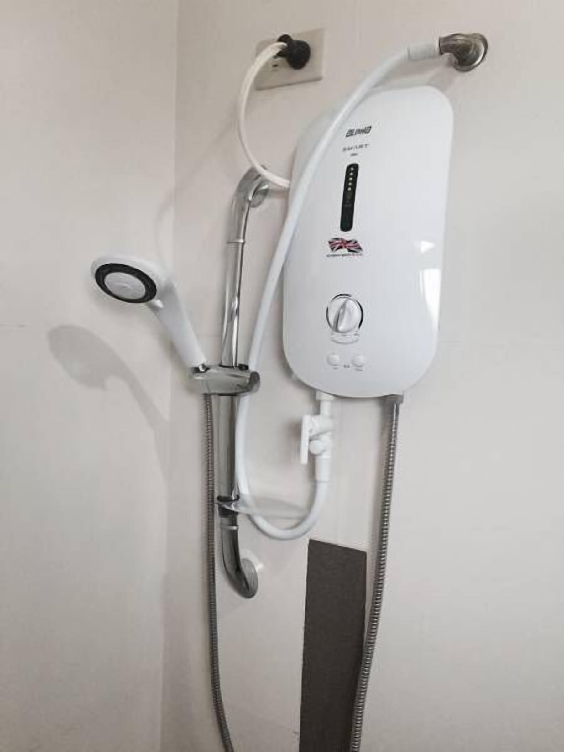 Una ducha empotrada con panel de control, cabezal de ducha manual y manguera flexible.