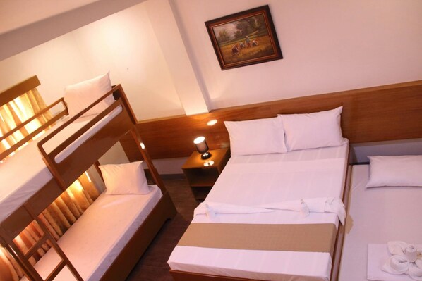 A hotel room with a bunk bed, a single bed, and a nightstand with a lamp. - Casa Belina Tourist Inn (Puerto Princesa)