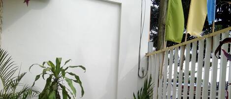 A patio with white metal chairs and a table, surrounded by potted plants.