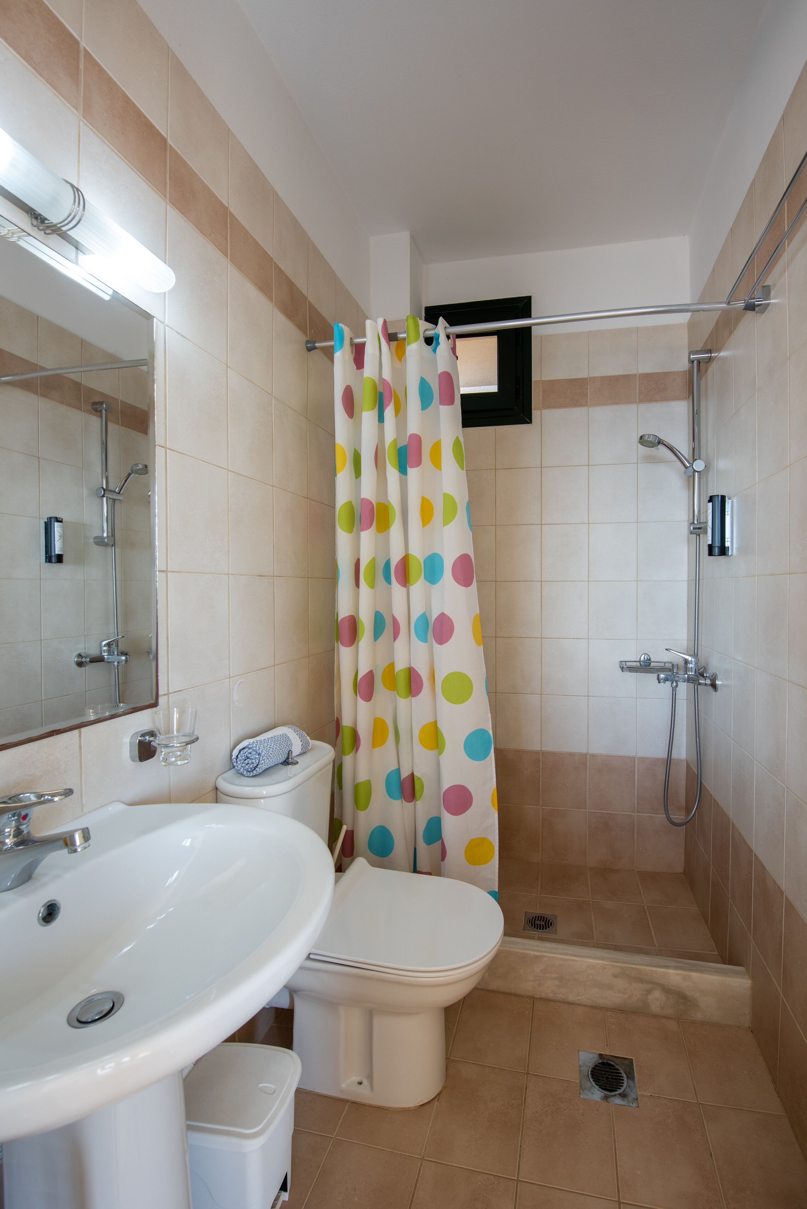 Une salle de bain équipée d’une douche, de toilettes, d’un lavabo et d’un miroir.