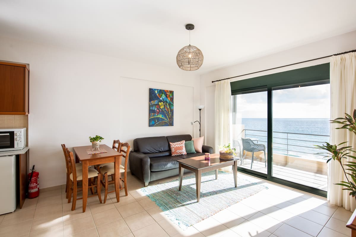 Un salon comprenant un coin repas, un canapé, une table basse et une vue sur la mer.