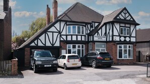 Un hotel de estilo Tudor con un letrero que dice "Pickering Park Hotel". Hay tres coches estacionados adelante.