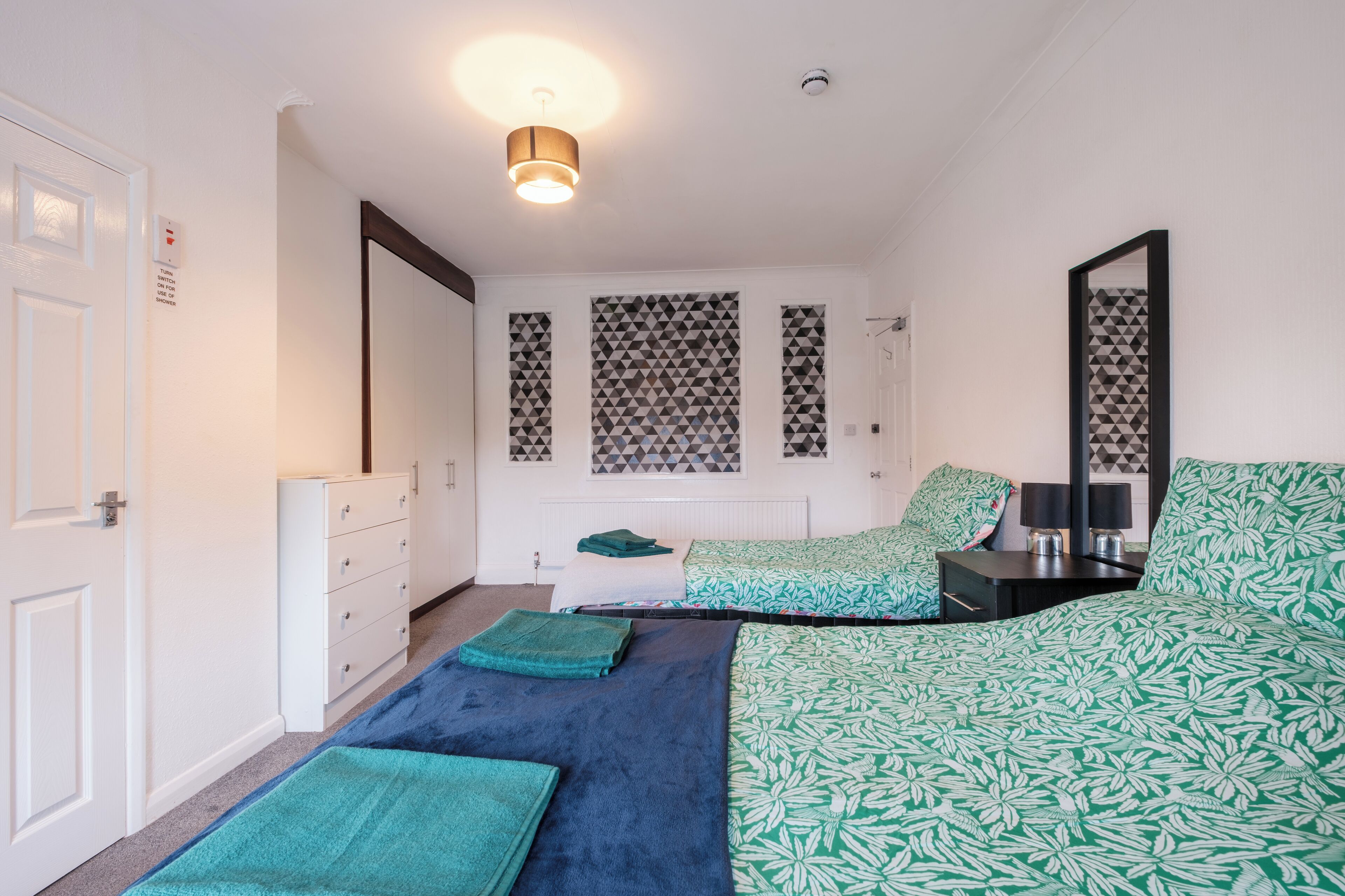 Un dormitorio con cama, cómoda, mesita de noche y espejo.