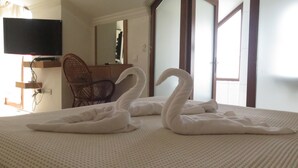 A bed with two swan-shaped towels and a television on the wall. - Lidya City Hotel (Fethiye)