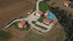 Vue aérienne d’un quartier résidentiel comprenant plusieurs maisons, une piscine et un court de tennis.