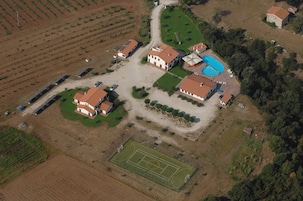 Vista aérea de una zona residencial con varias casas, una piscina y una cancha de tenis.