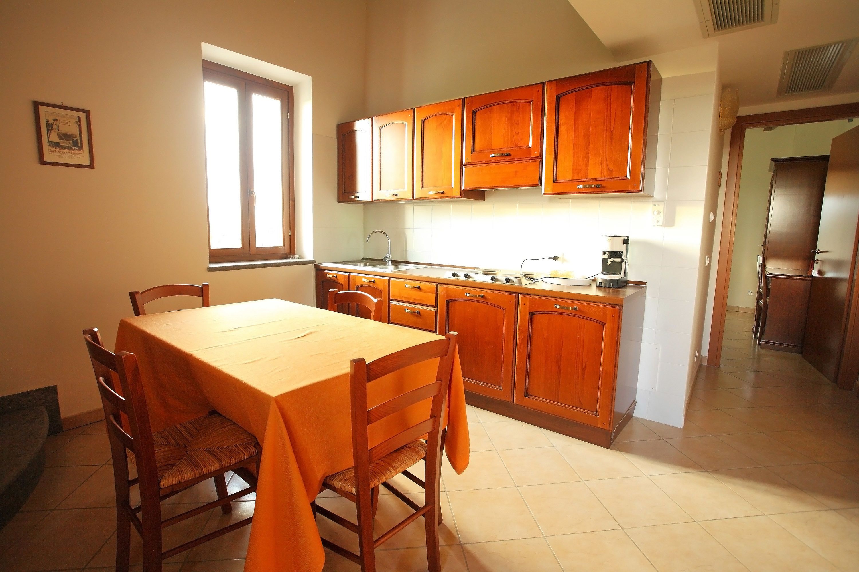 A kitchen with wooden cabinets, a dining table, chairs, and a window.