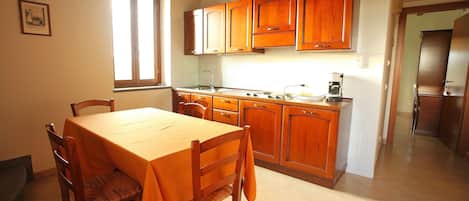 A kitchen with wooden cabinets, a dining table, chairs, and a window.