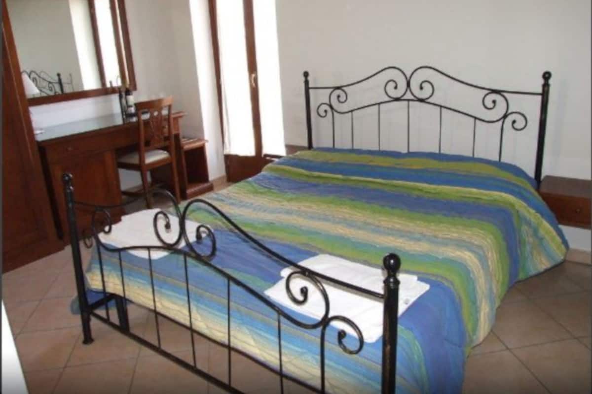 Een slaapkamer met een metalen bedframe, een houten dressoir en een spiegel.