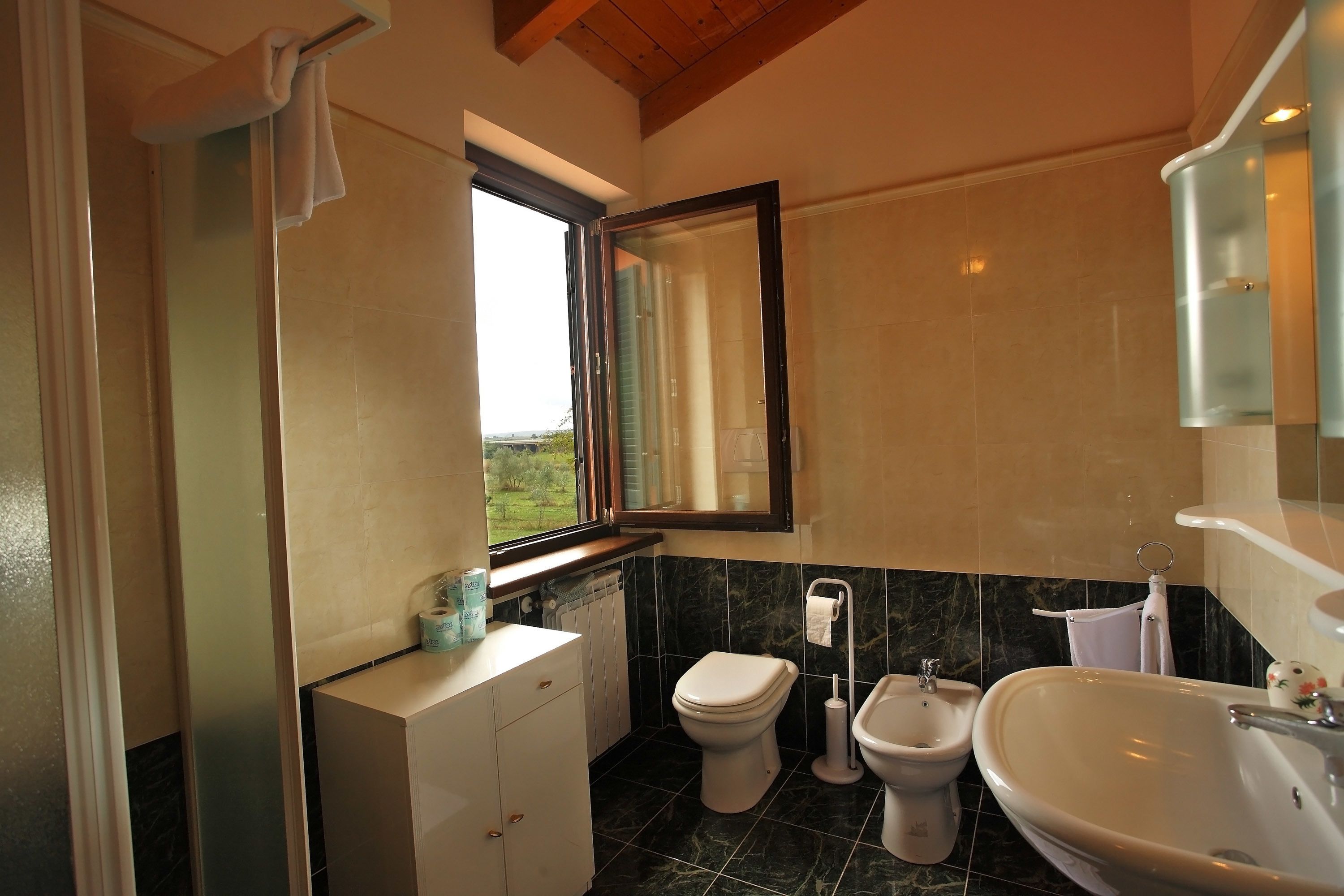 Un baño con inodoro, bidé y lavamanos, una ventana y un espejo.