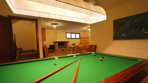 Une table de billard avec des queues et des billes, un meuble en bois et un tableau accroché au mur.