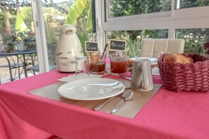 Une table dressée avec une assiette blanche, des couverts, une cafetière et deux verres à thé étiquetés.