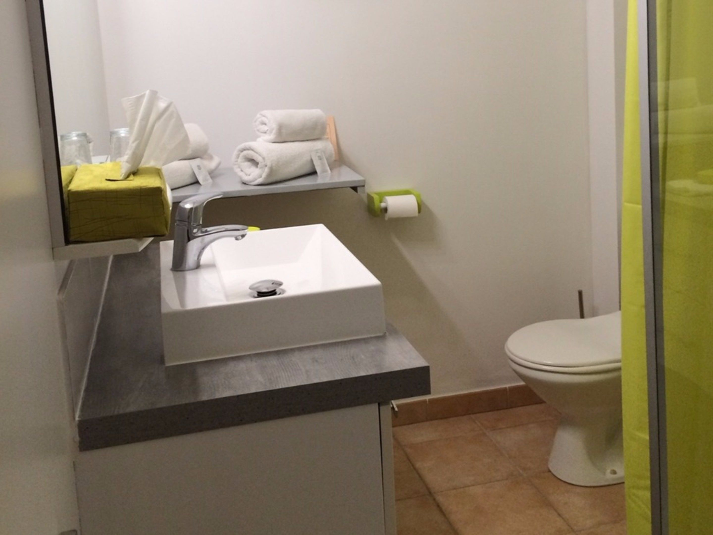 A modern bathroom with a white sink, a mirror, a towel rack, and a toilet.