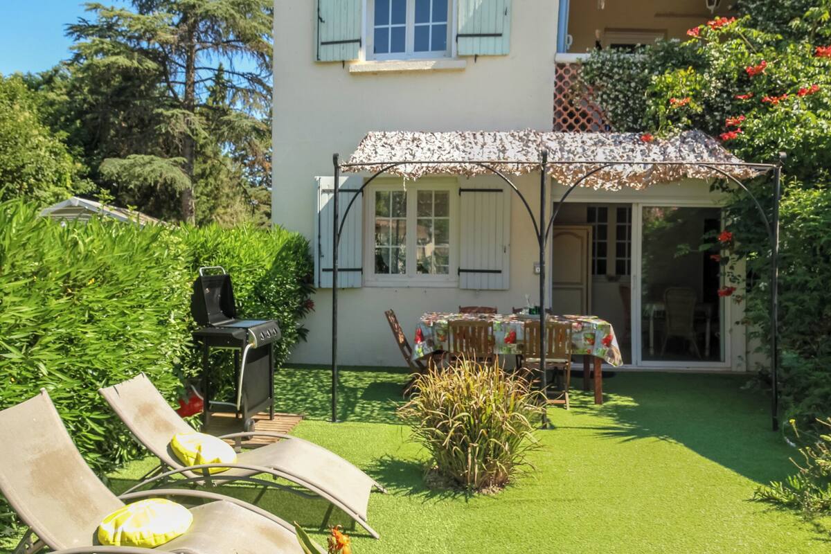 A garden with a patio, a table, and chairs.