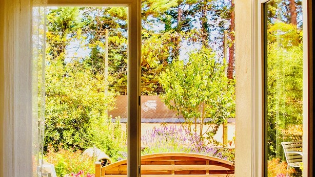 Una stanza con vista su un giardino, attraverso una porta in vetro.