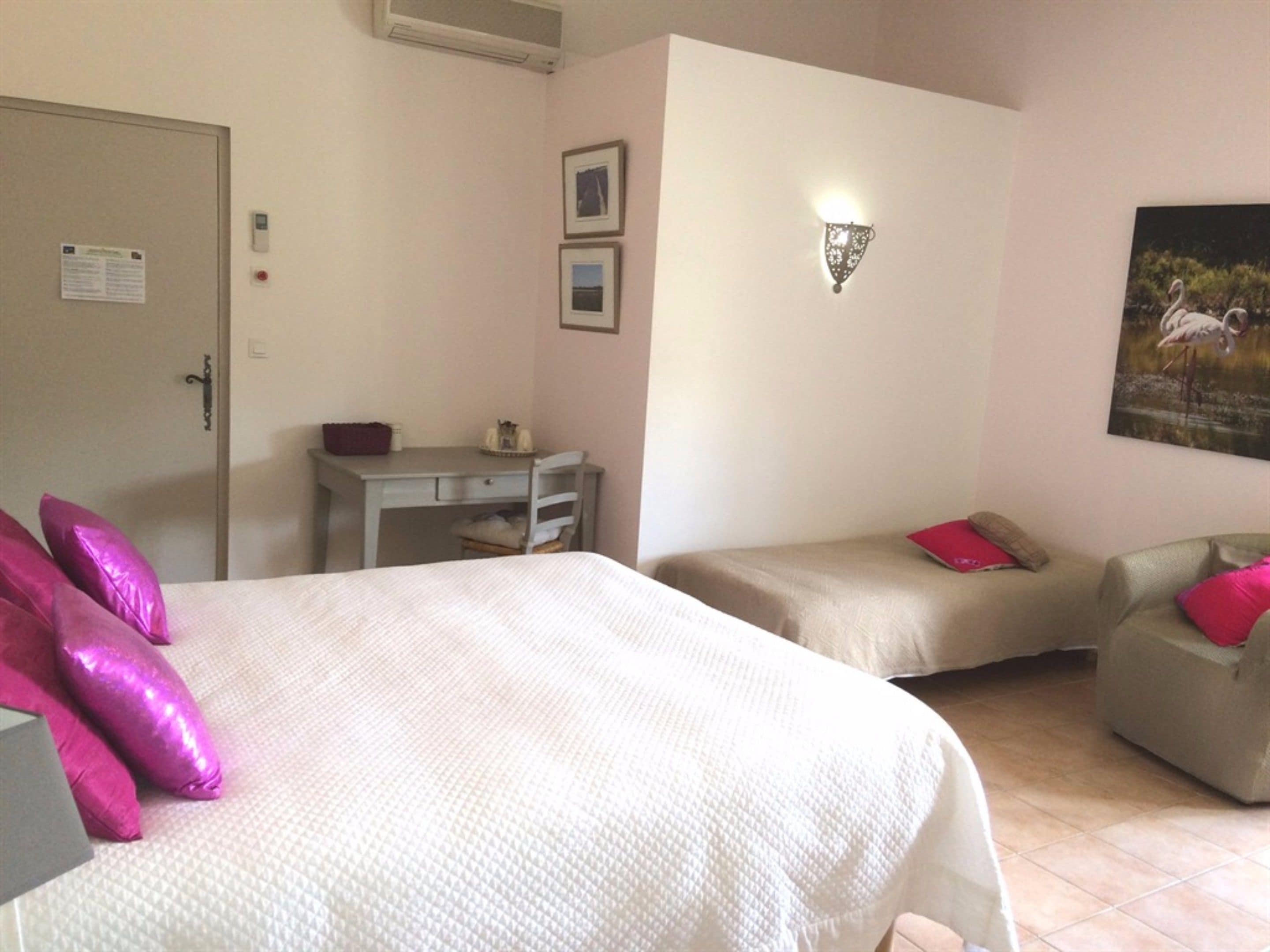 Une chambre d’hôtel avec deux lits, un bureau, une chaise et un luminaire fixé au mur.