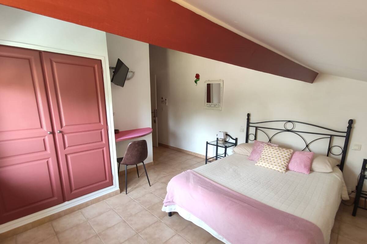 A bedroom with a bed, a desk, a chair, and a wardrobe.