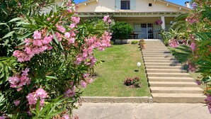 Una casa a due piani con un portico, una scalinata che conduce all'ingresso e un prato curato.