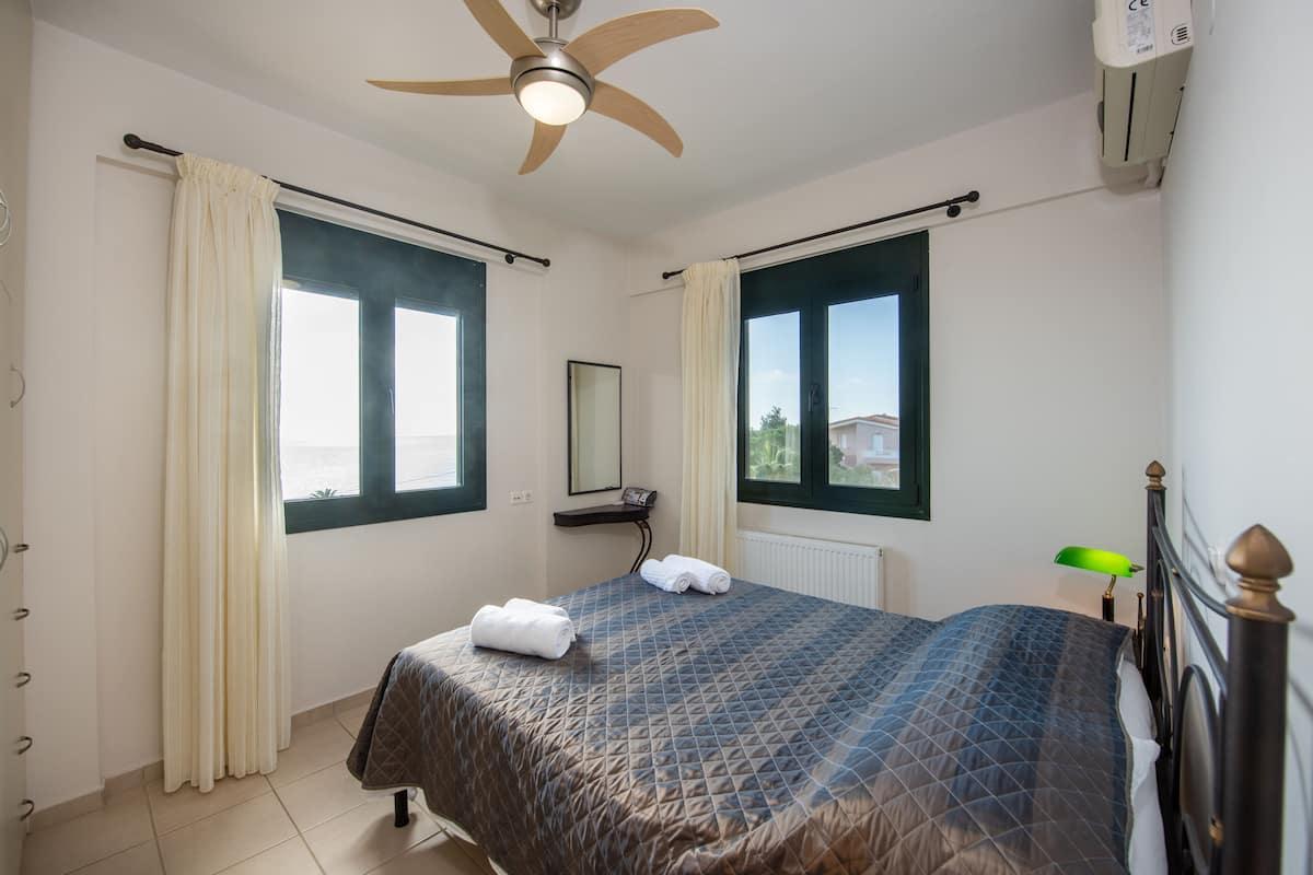 A bedroom with a bed, a ceiling fan, a window, and a radiator.