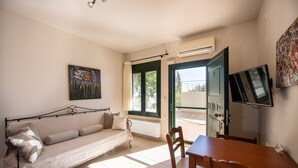Una habitación con sofá, mesa de comedor, televisor y ventana con cortinas.