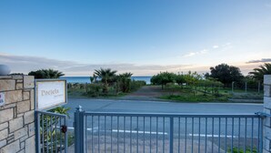 Una entrada con portón a Portela Apartments, con vista al mar y un cielo despejado.